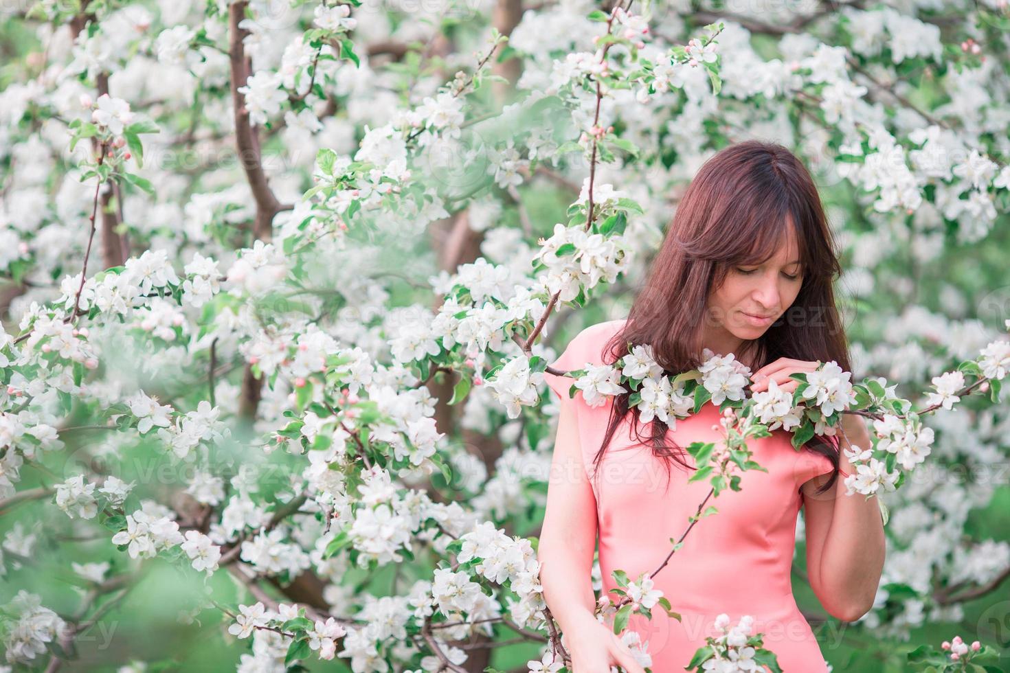 Beautiful woman enjoying smell in spring cherry garden photo