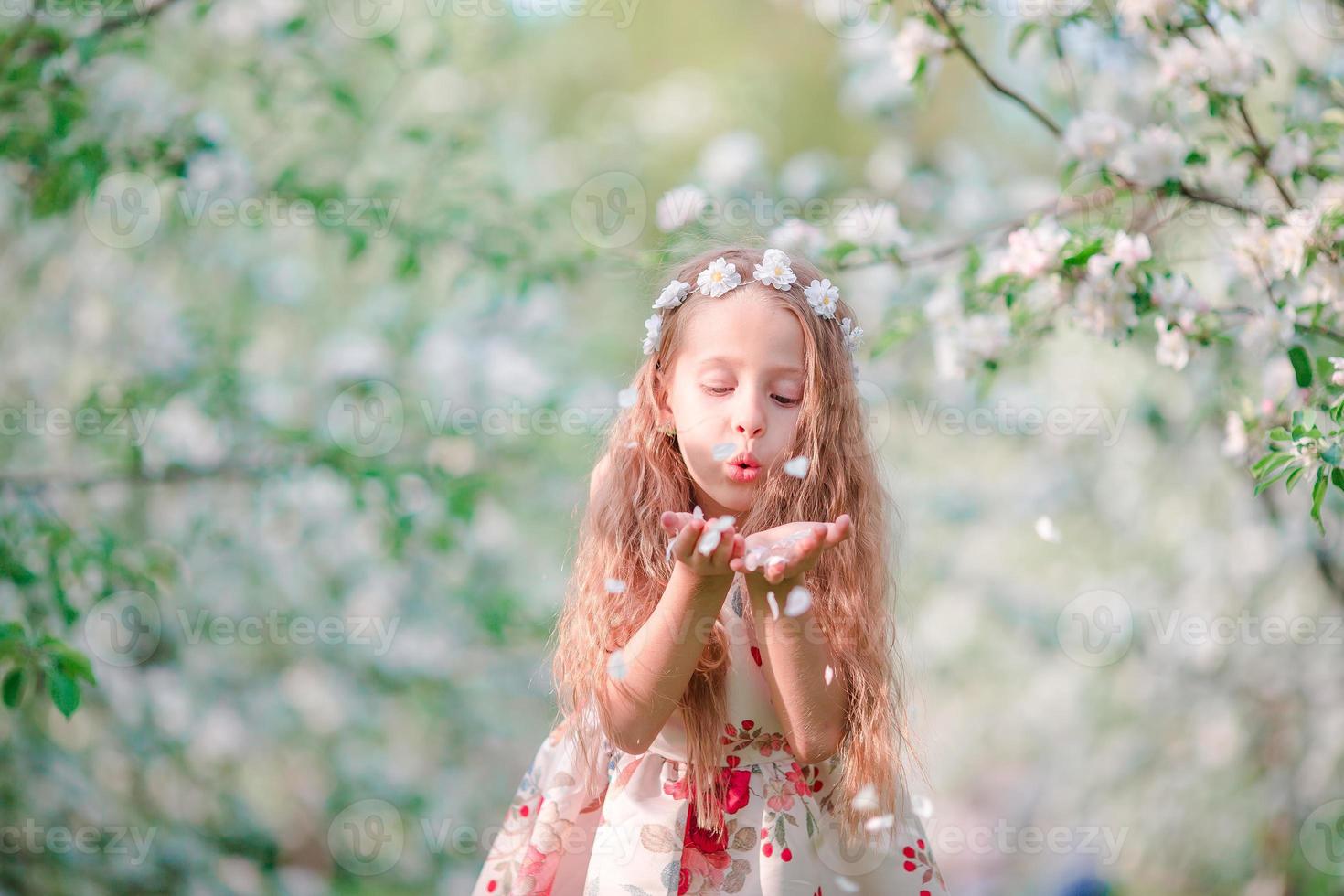 Adorable little girl in blooming cherry tree garden on spring day photo