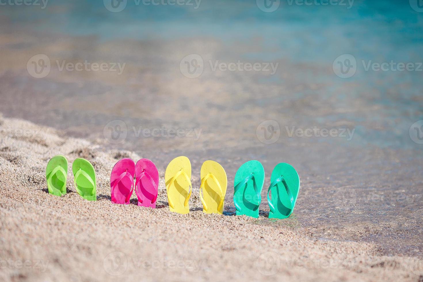 Family colorful flip flops on beach in front of the sea photo