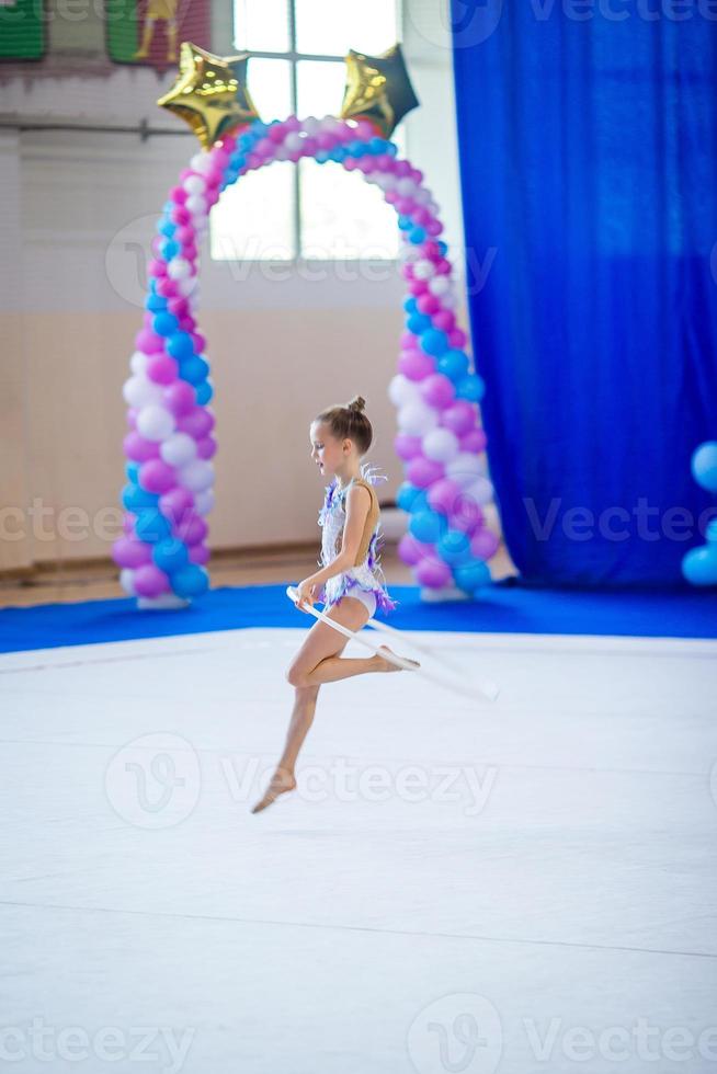 Beautiful little active gymnast girl with her performance on the carpet photo