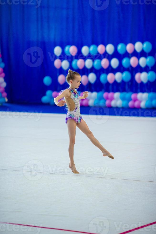 Beautiful little active gymnast girl with her performance on the carpet photo