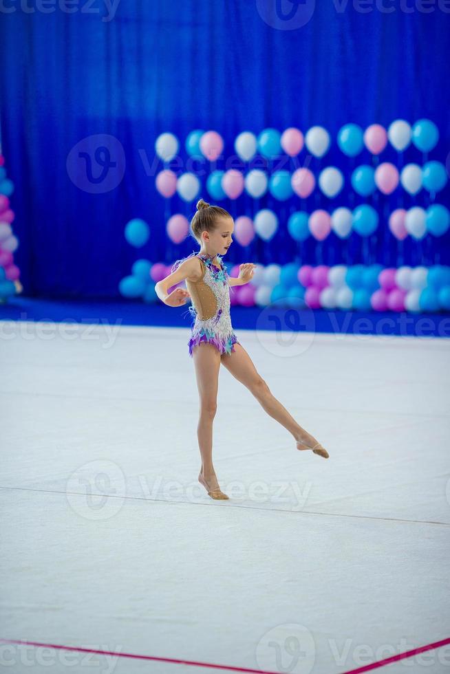 hermosa niña gimnasta activa con su actuación en la alfombra foto