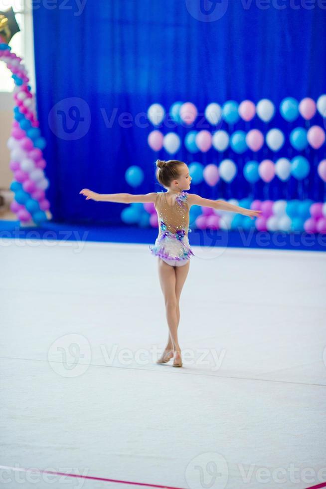 Beautiful little active gymnast girl with her performance on the carpet photo