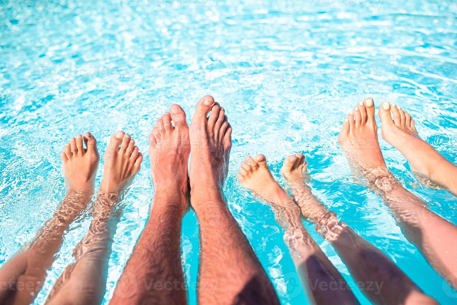 Close up of four people's legs by pool side photo