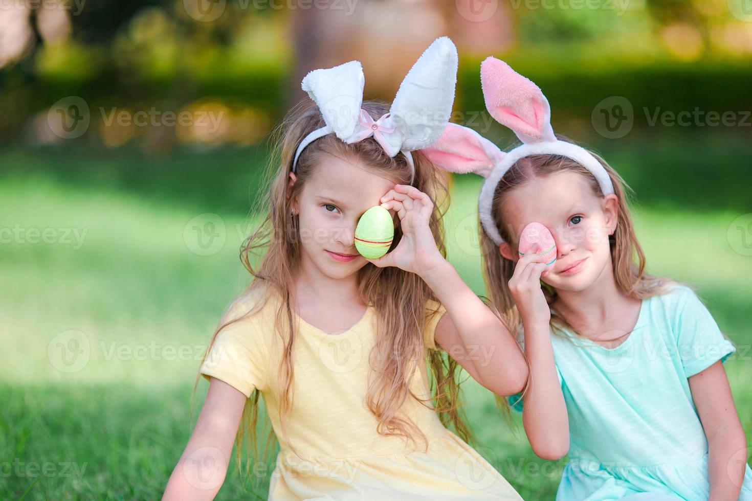 dos adorables hermanitas con orejas de conejo el día de pascua al aire libre foto