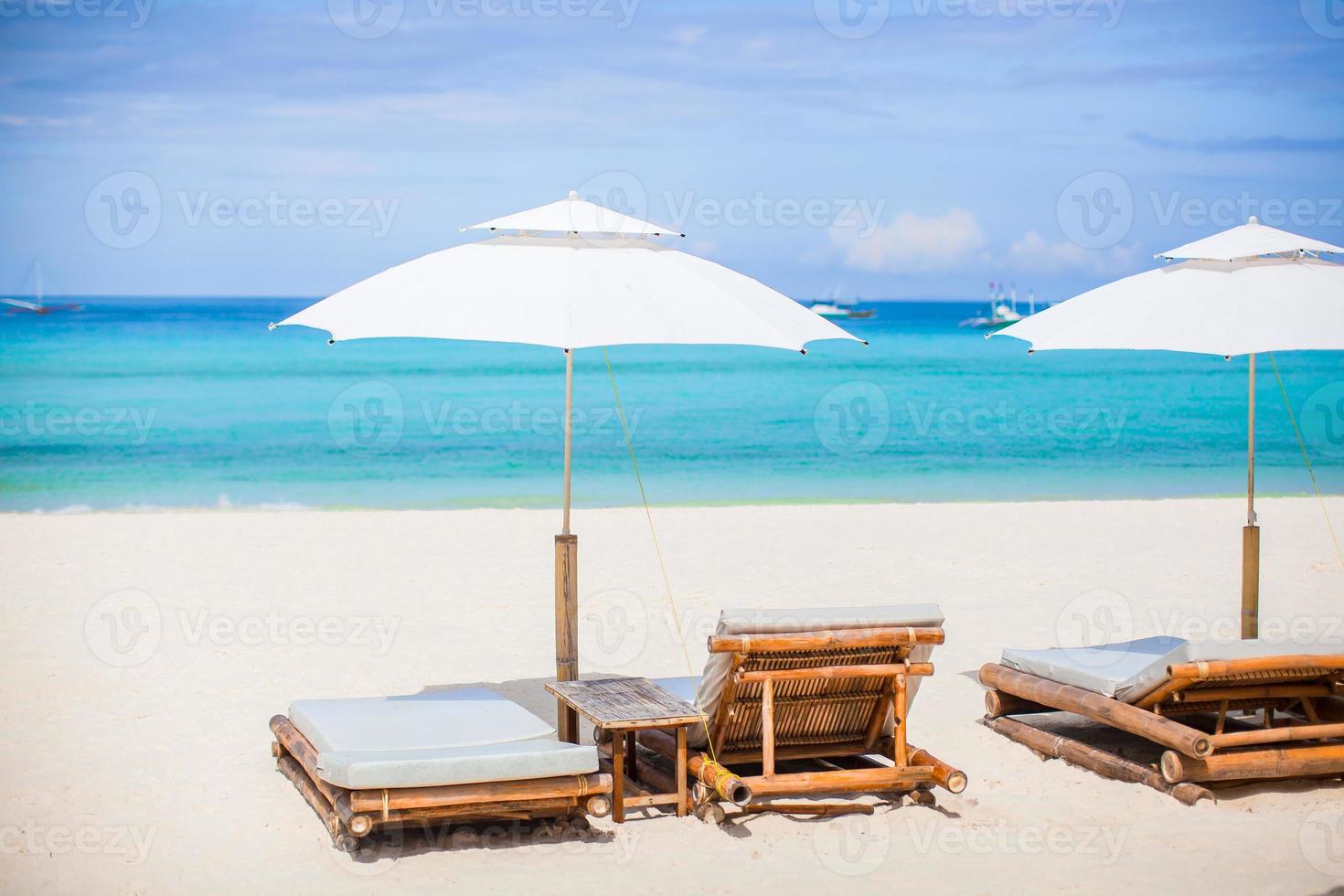Beach chairs and umbrella on exotic tropical white sandy beach photo