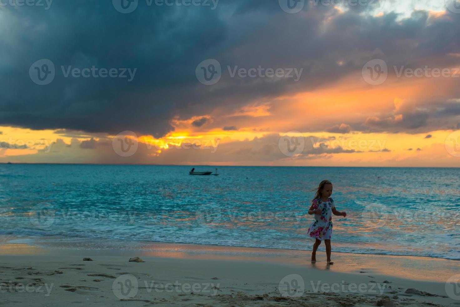 niña adorable caminando en la hermosa puesta de sol durante la playa foto