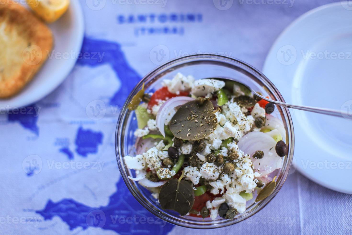 Greek salad on the table with map of Santorini, Greece photo