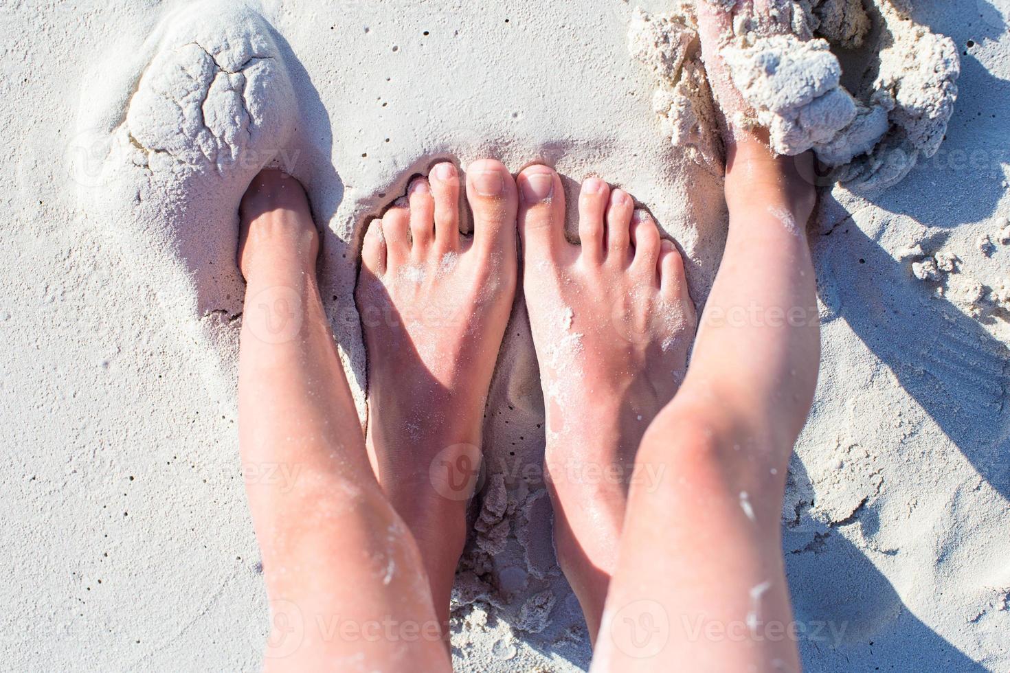 Closeup feet of mother and kid on white sand beach photo