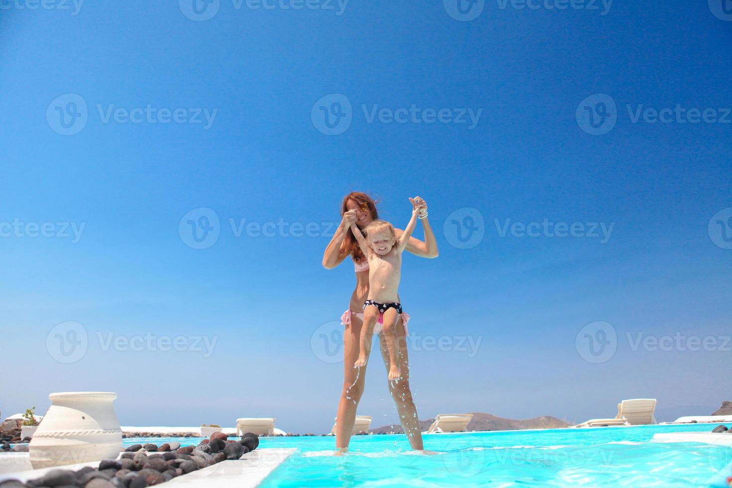 Young mother and little daughter have fun near the swimming pool photo