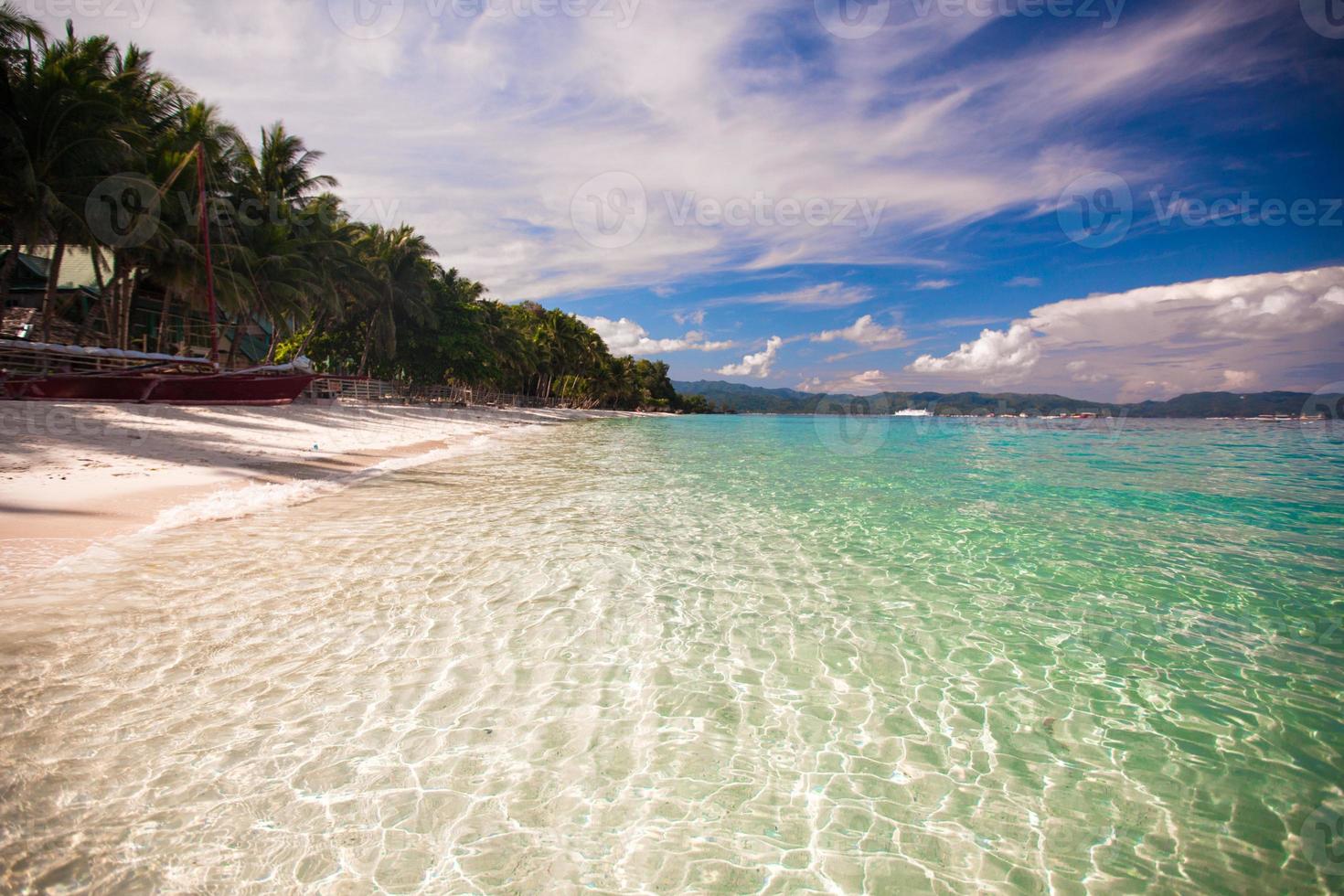 Tropical beach with white sand and a small boat photo