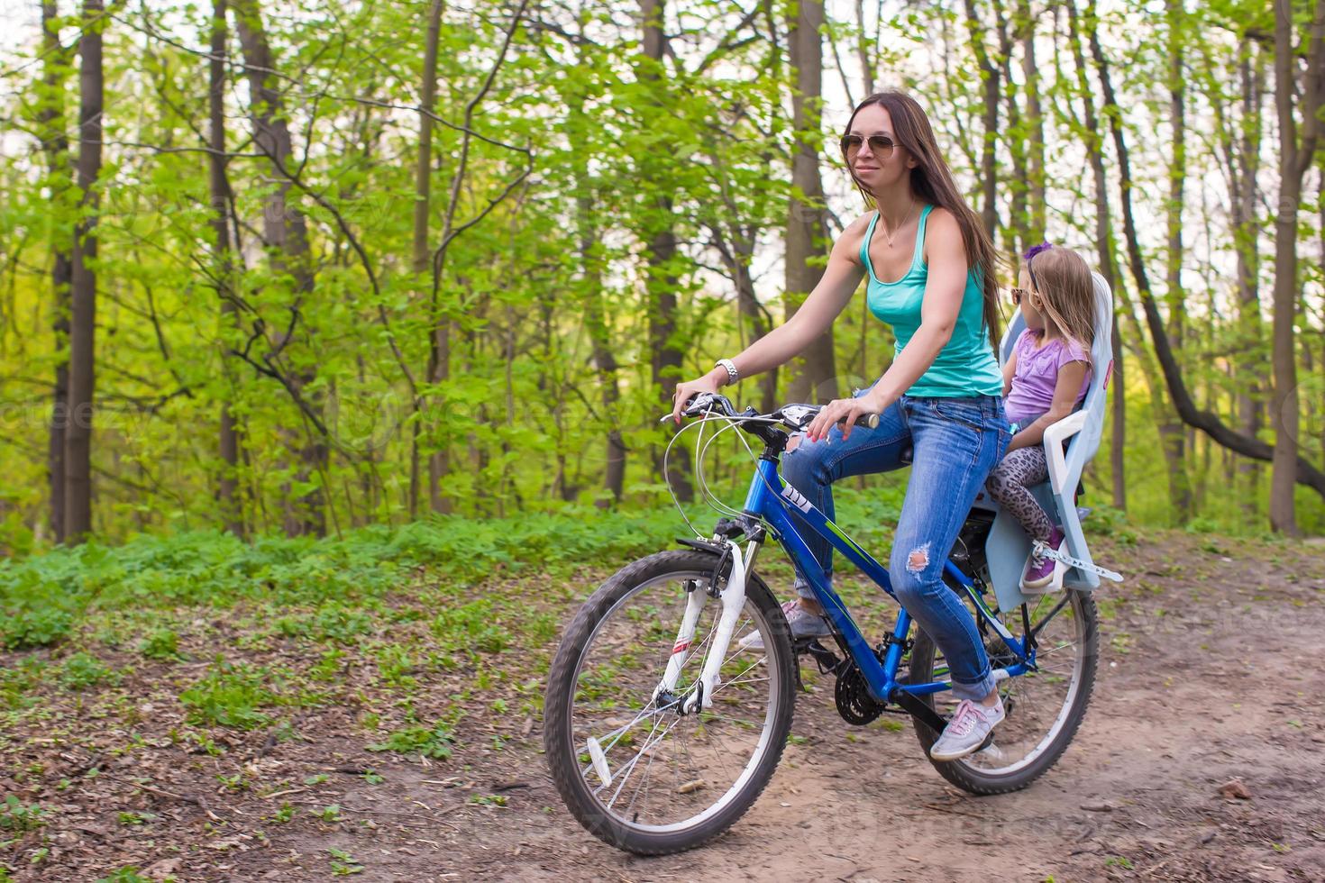 feliz madre y pequeña hija en bicicleta en el parque foto