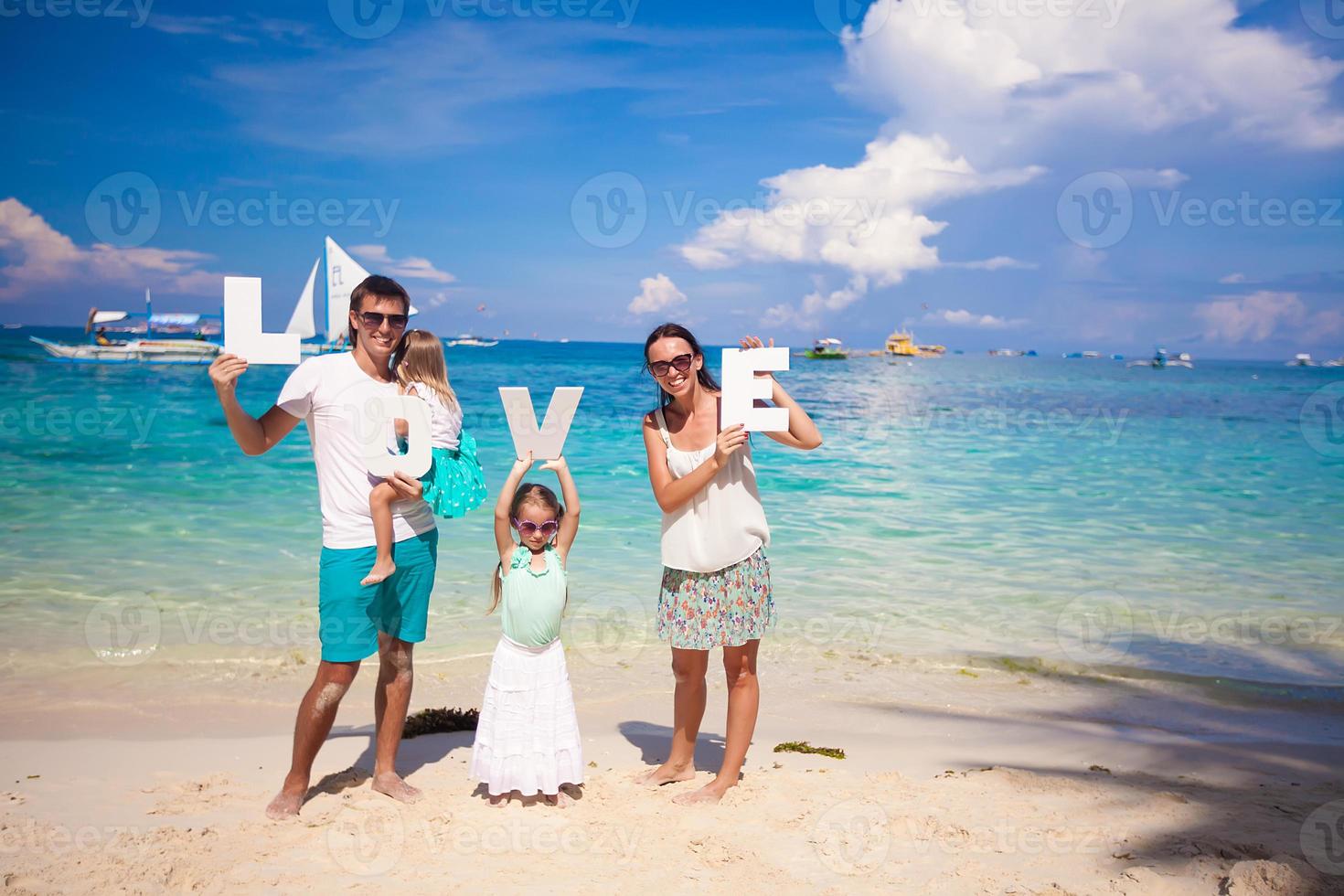 Young happy family and two kids with word LOVE on tropical vacation photo