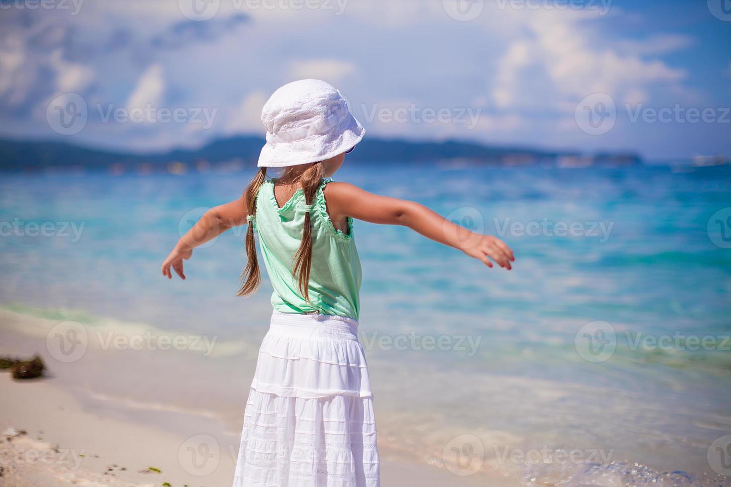 Adorable happy little girl on beach vacation walking squaring arm photo