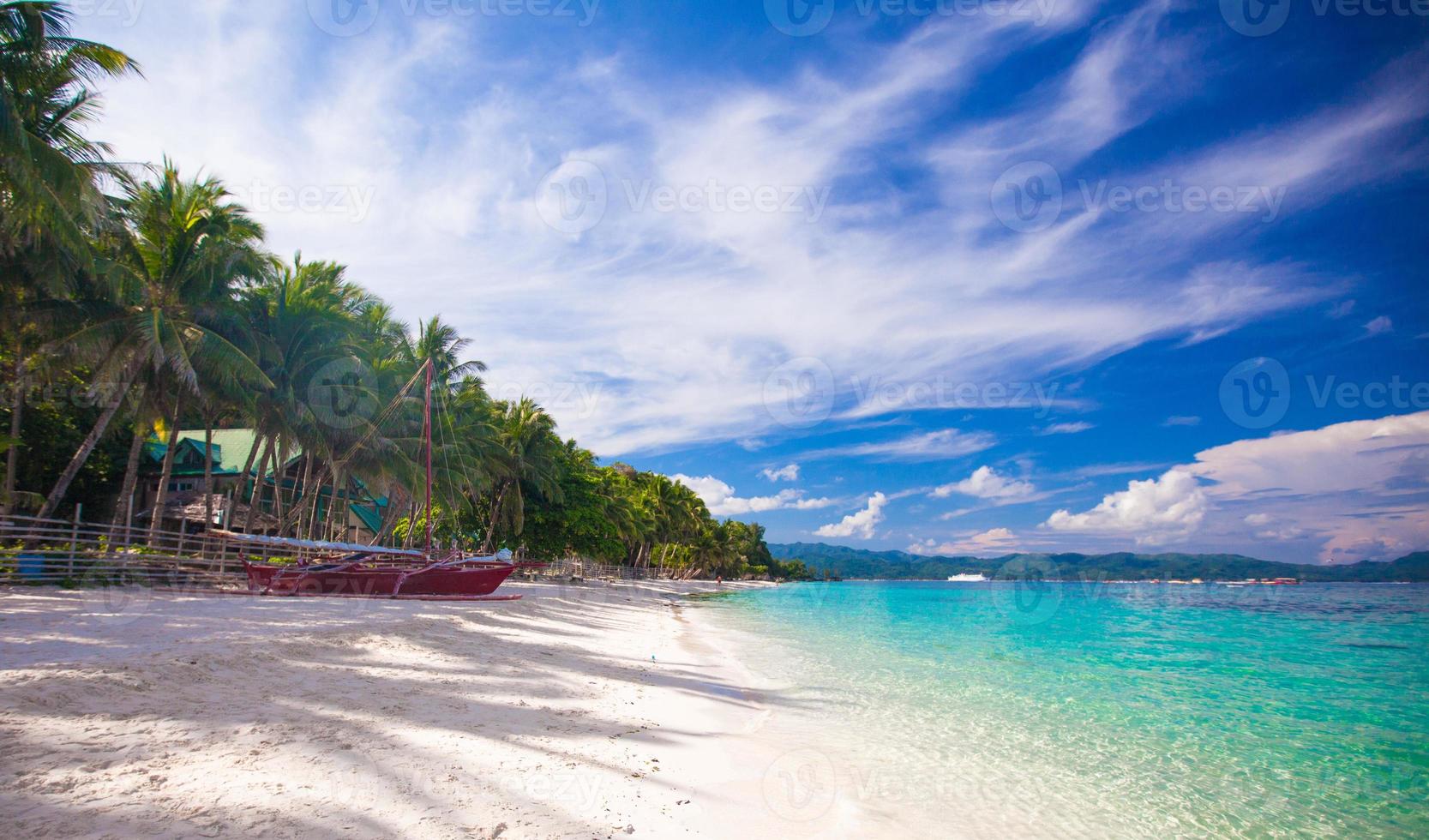 Tropical beach with white sand and a small boat photo