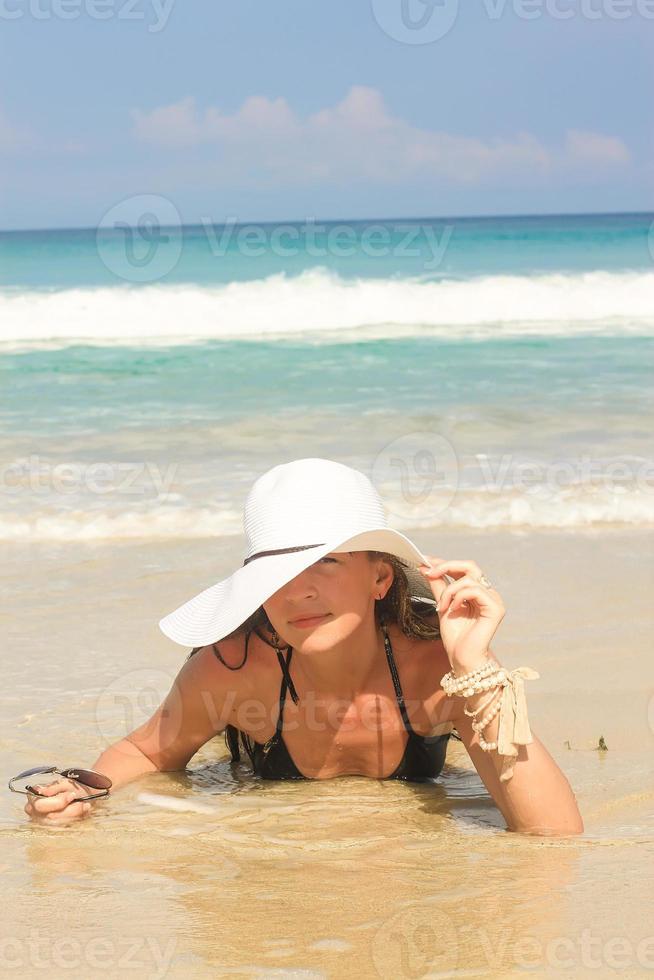 Young woman on beach holding hat enjoying summer holidays photo