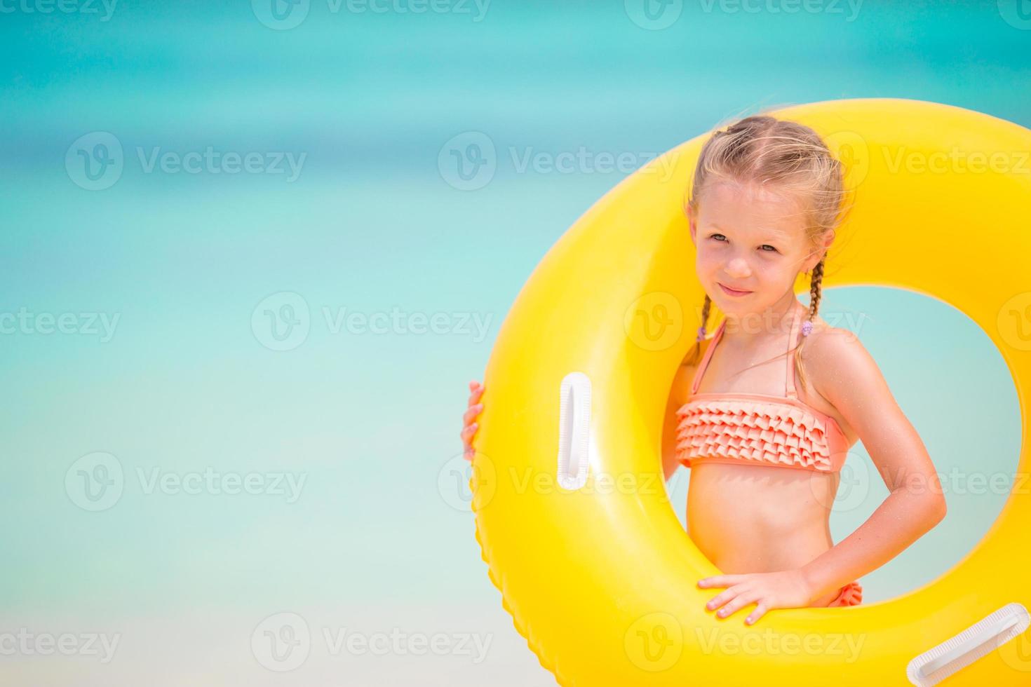 Adorable girl with inflatable rubber circle on white beach photo