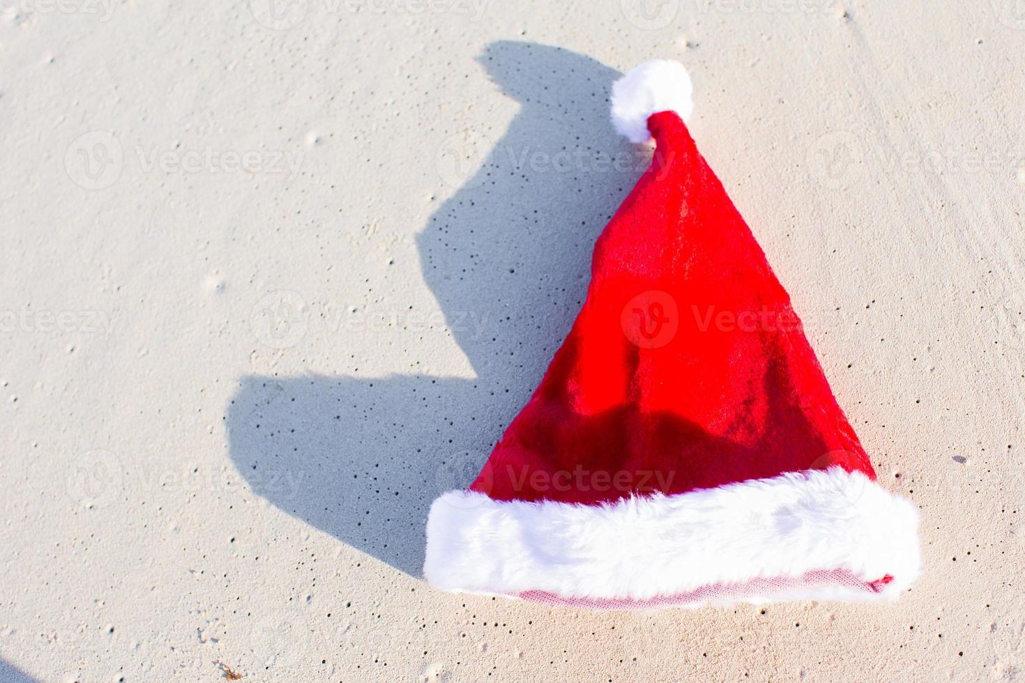 Cierra el gorro de Papá Noel en una playa de arena blanca. foto