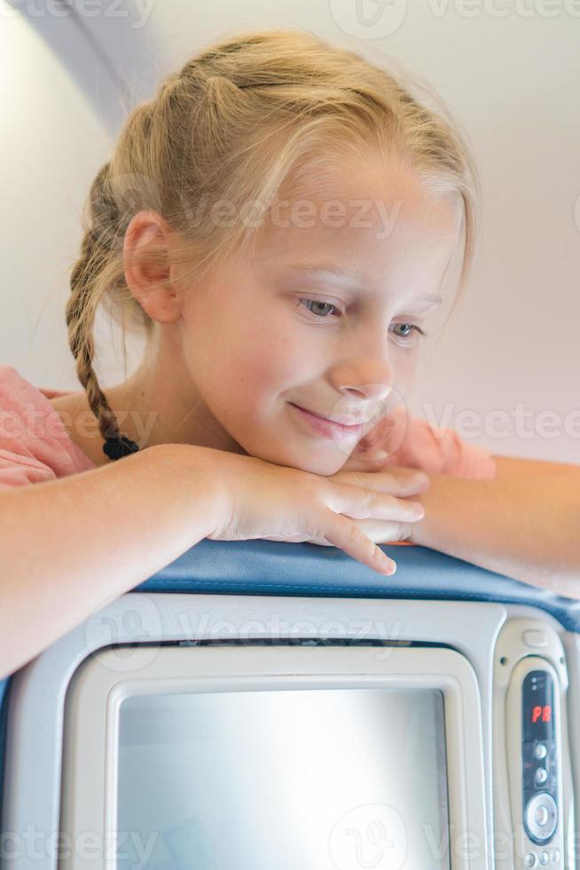 adorable niña viajando en avión y sonriendo foto