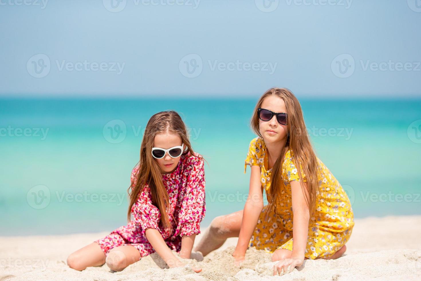 Little happy funny girls have a lot of fun at tropical beach playing together. photo