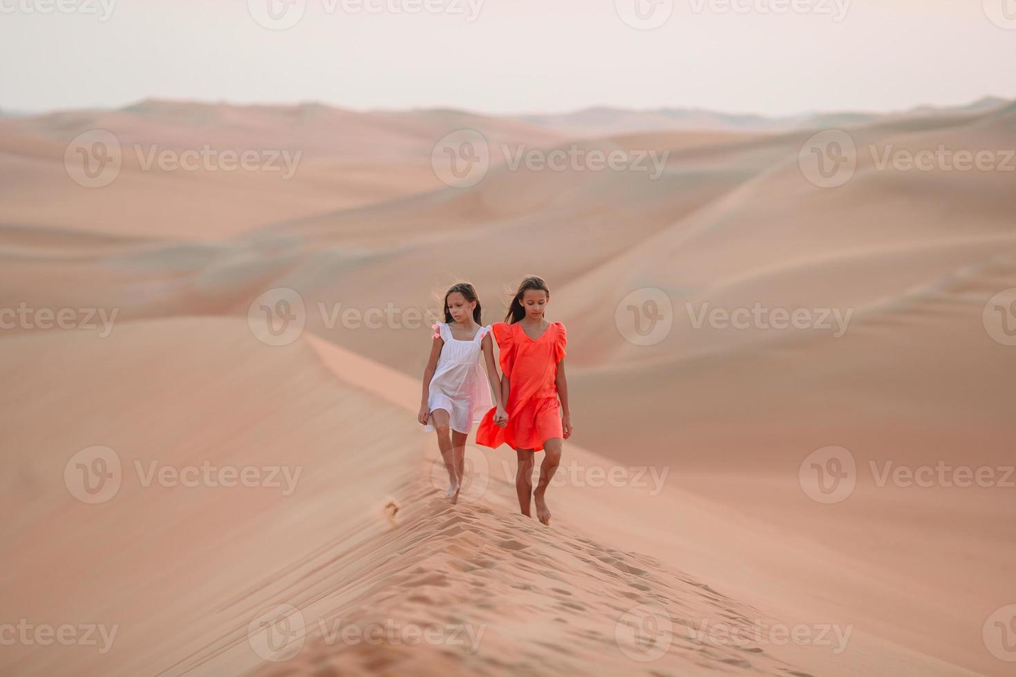 Girls among dunes in Rub al-Khali desert in United Arab Emirates photo