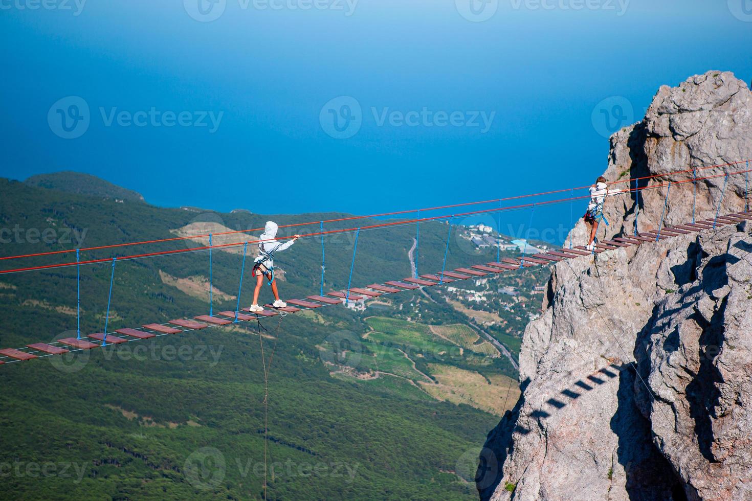 Girls crossing the chasm on the rope bridge. Black sea background, Crimea, Russia photo