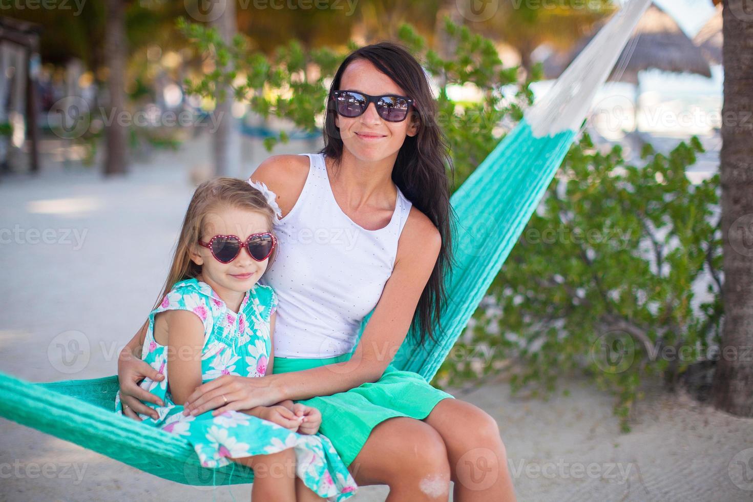 mamá joven y niña en vacaciones tropicales relajándose en hamaca foto