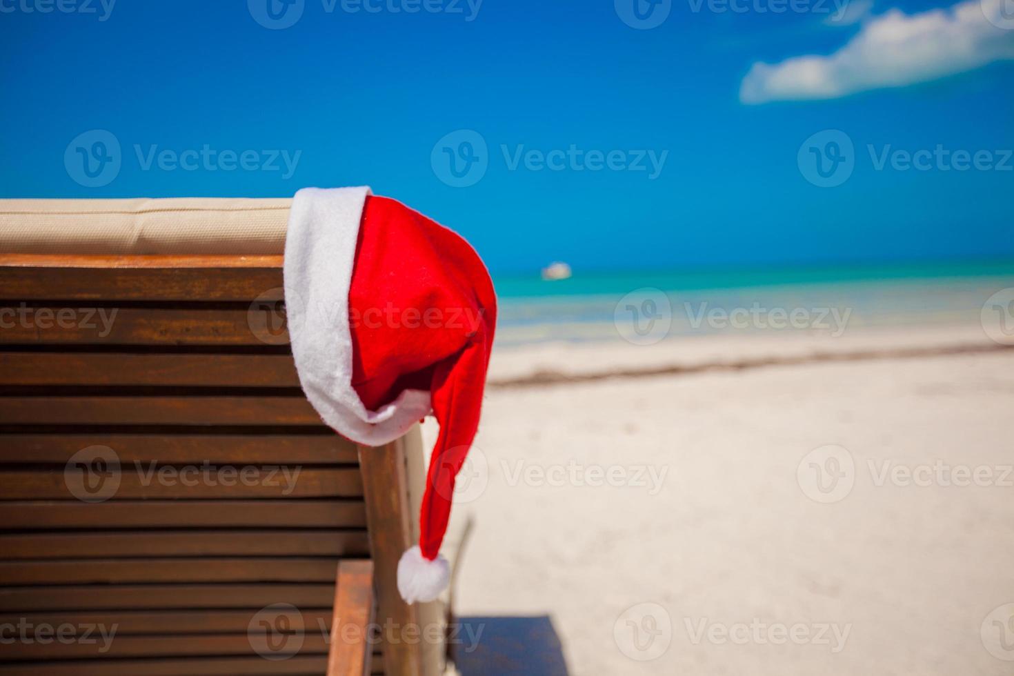 primer plano de gorro de Papá Noel en silla longue en playa caribeña tropical foto