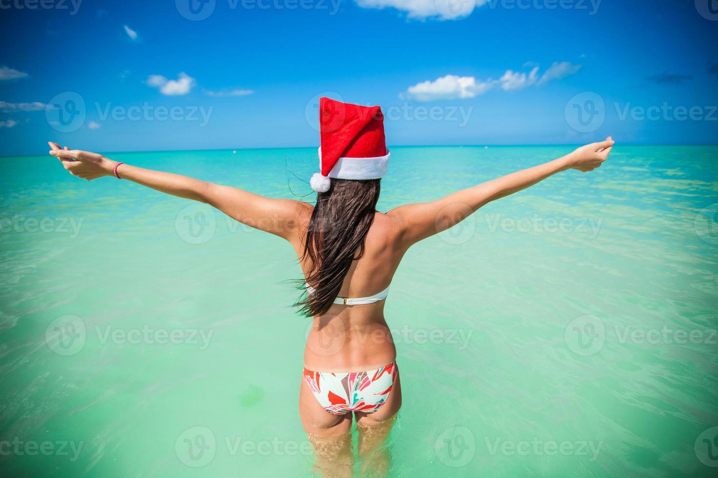 Back view of beautiful girl in santa hat walking like a bird photo