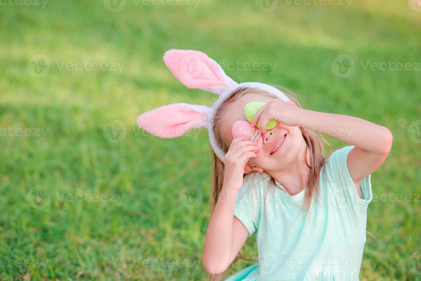 Adorable little girl on Easter holiday sitting on the grass photo