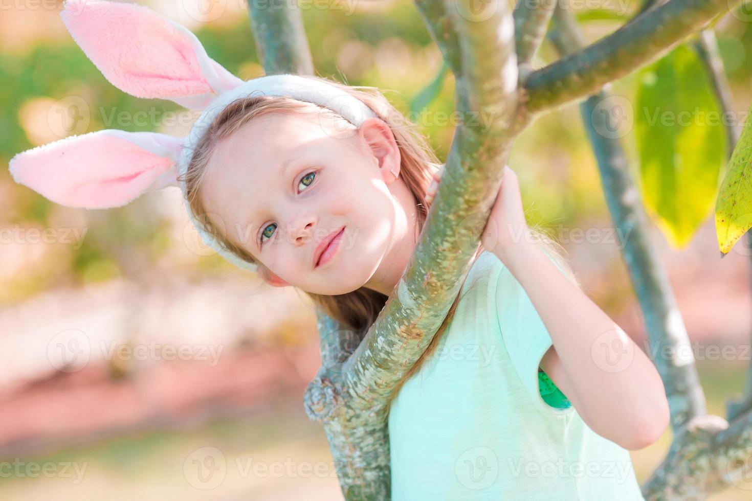 adorable niña con orejas de conejo en pascua en el día de la primavera foto