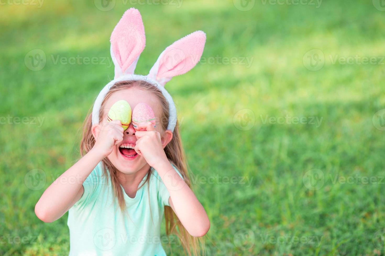 Adorable little girl on Easter holiday sitting on the grass photo