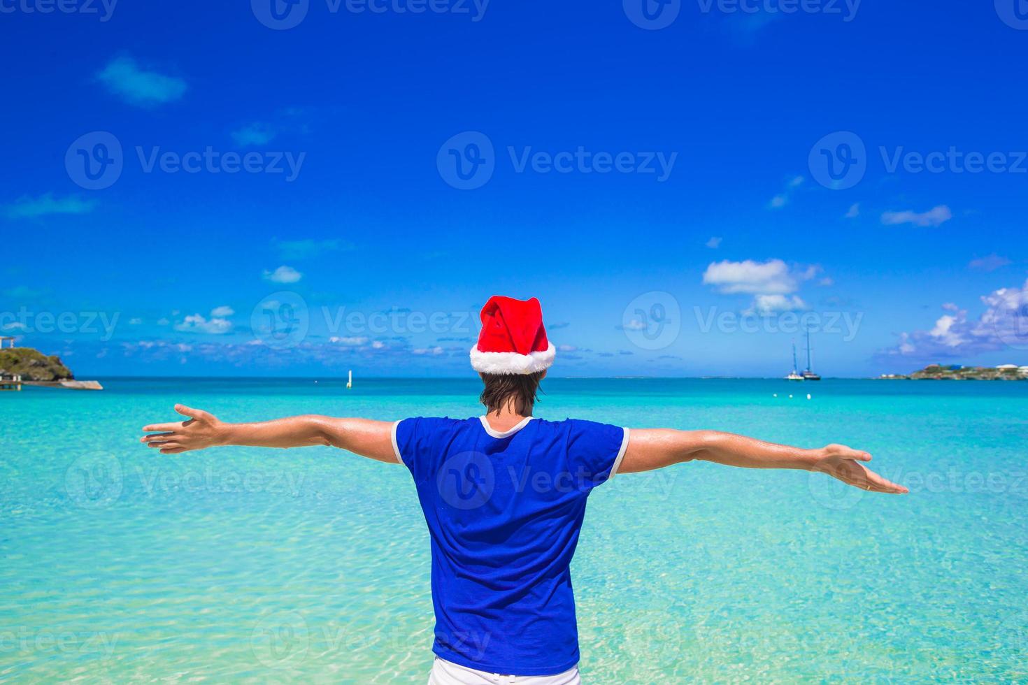 Young man in red santa hat on tropical beach photo