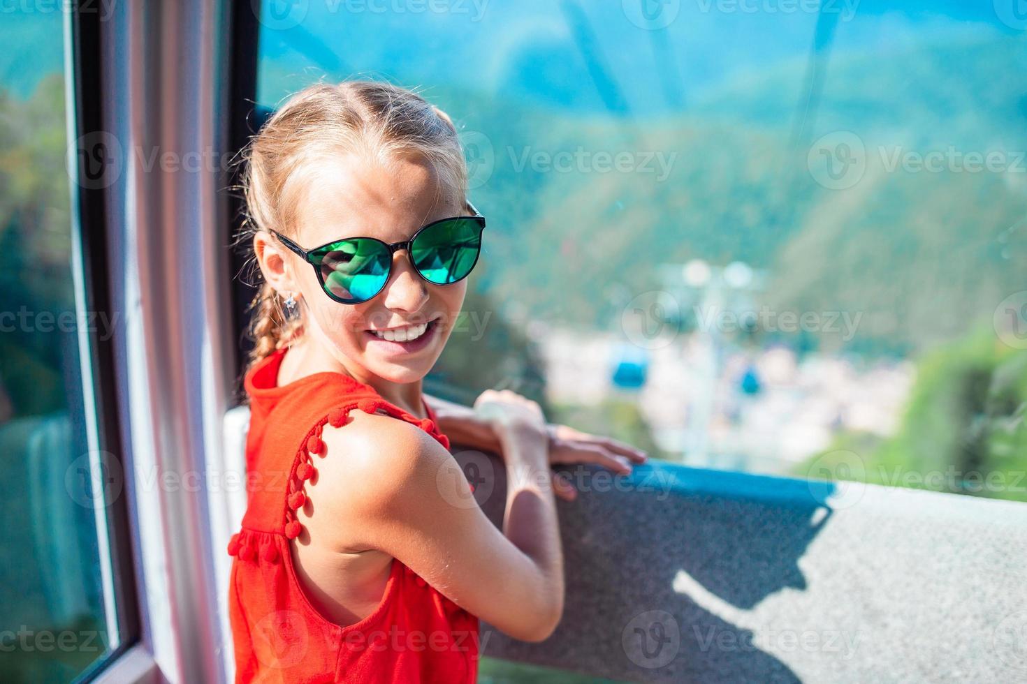 adorable niña en la cabina del teleférico en las montañas foto