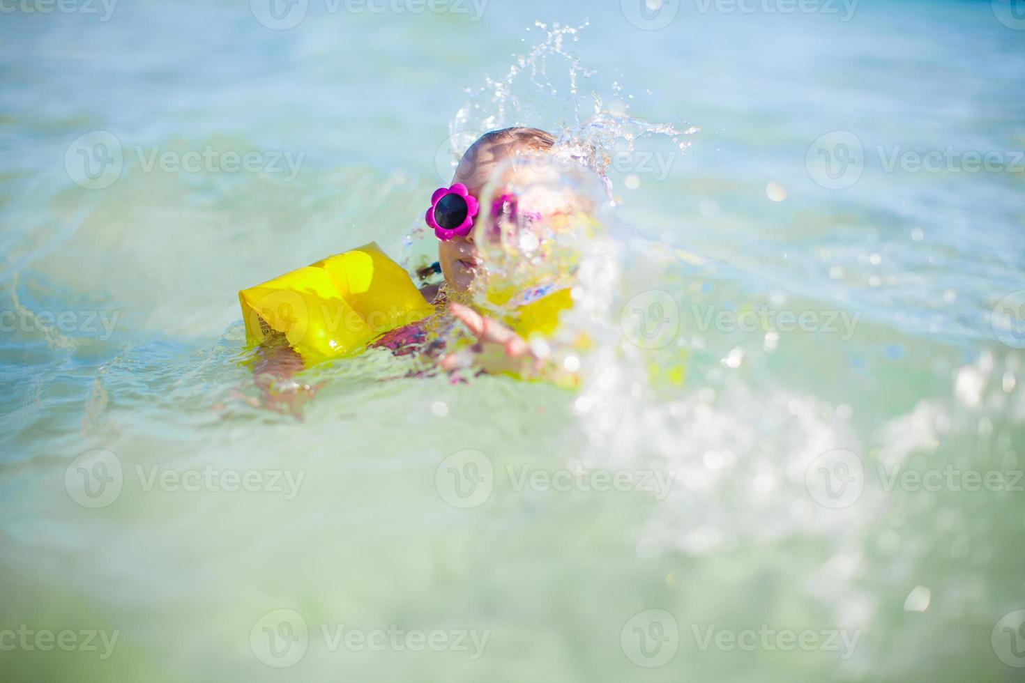 Little happy girl at swimsuit having fun in clear sea photo