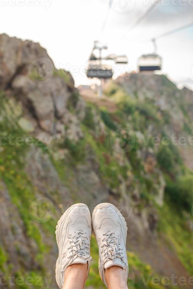 Close-up of female legs in sneakers on the grass outdoors in the park photo