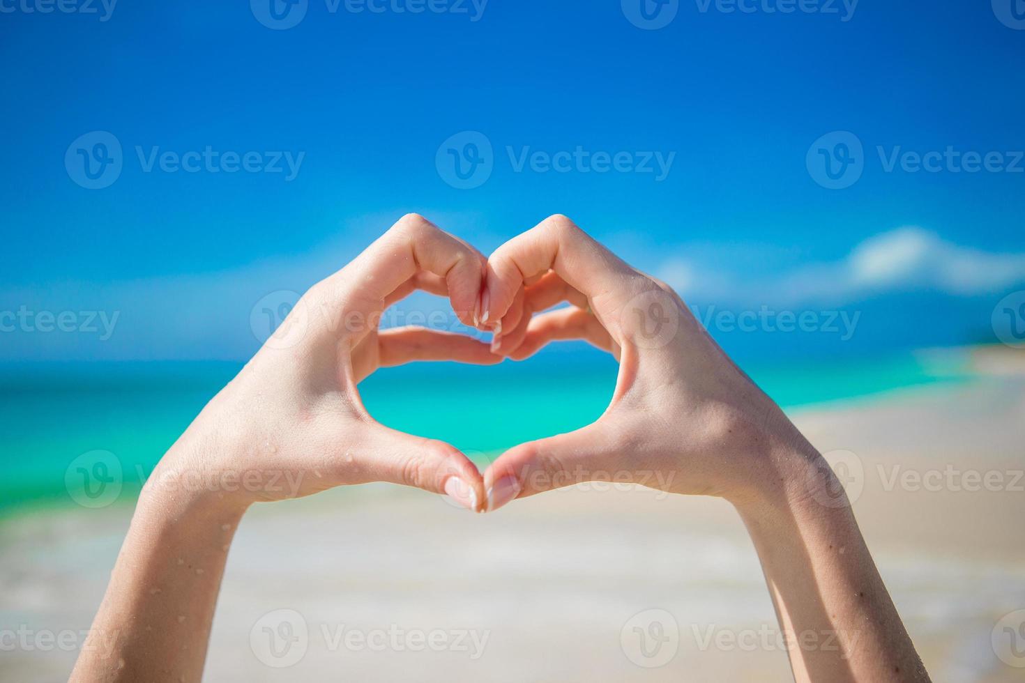 Close up of heart made by female hands background the turquoise ocean photo