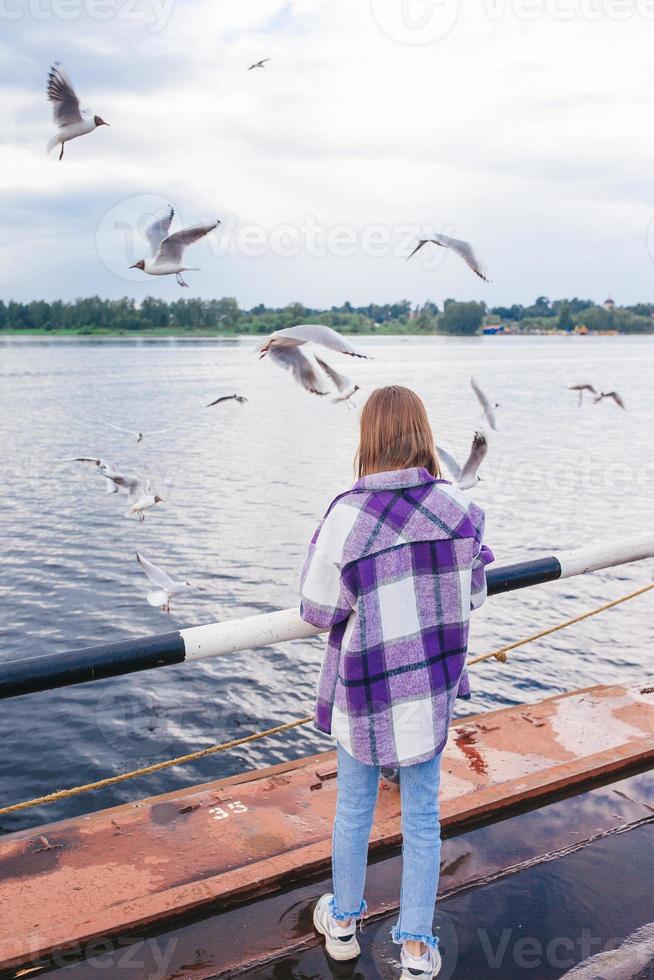 Cute little girl feed seagulls photo