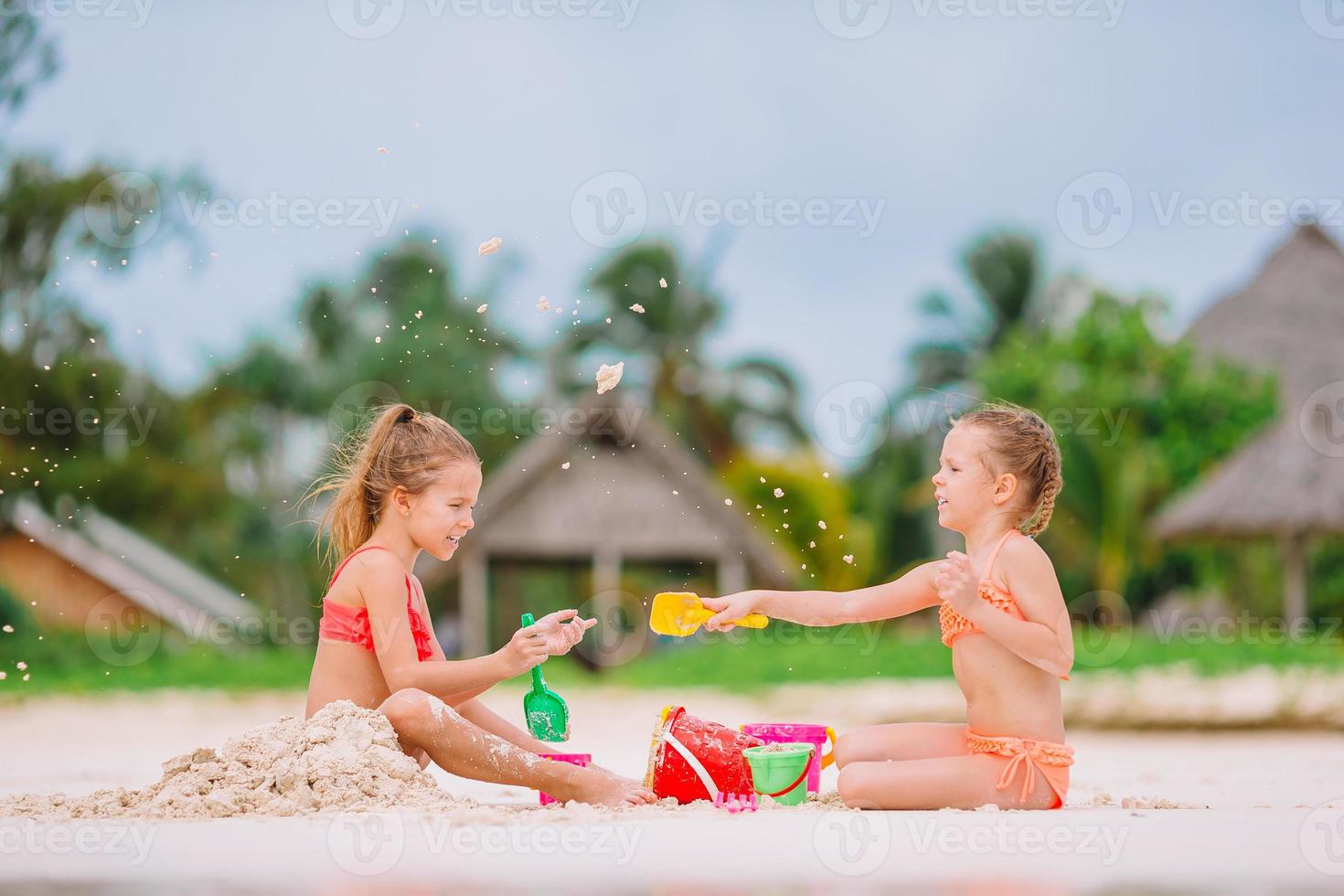 Two kids making sand castle and having fun at tropical beach photo