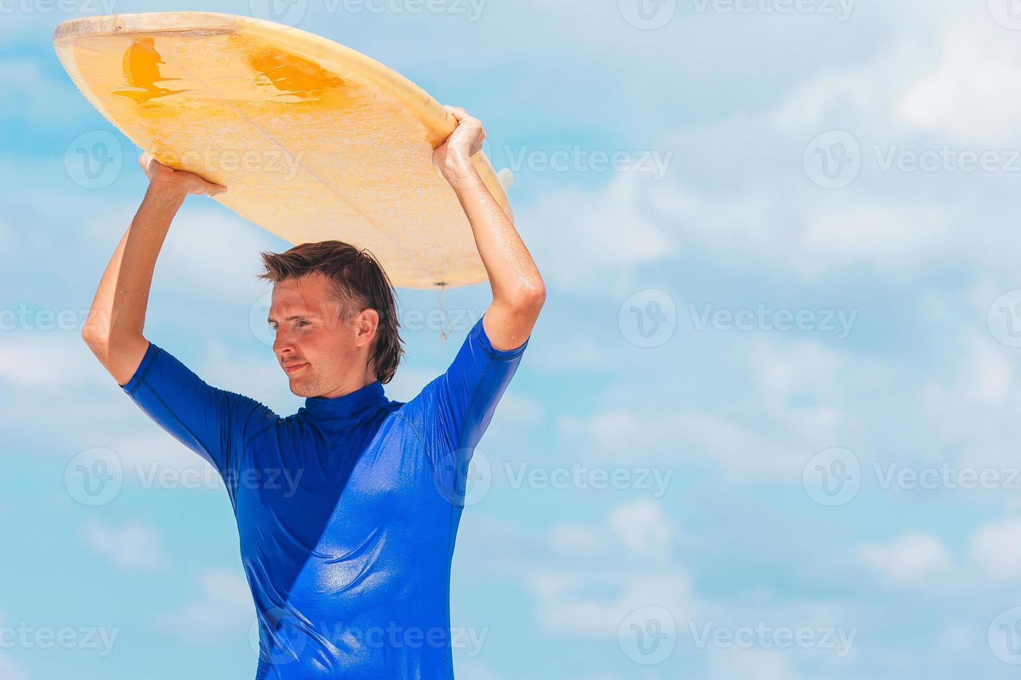 Young surf man at white beach with yellow surfboard photo