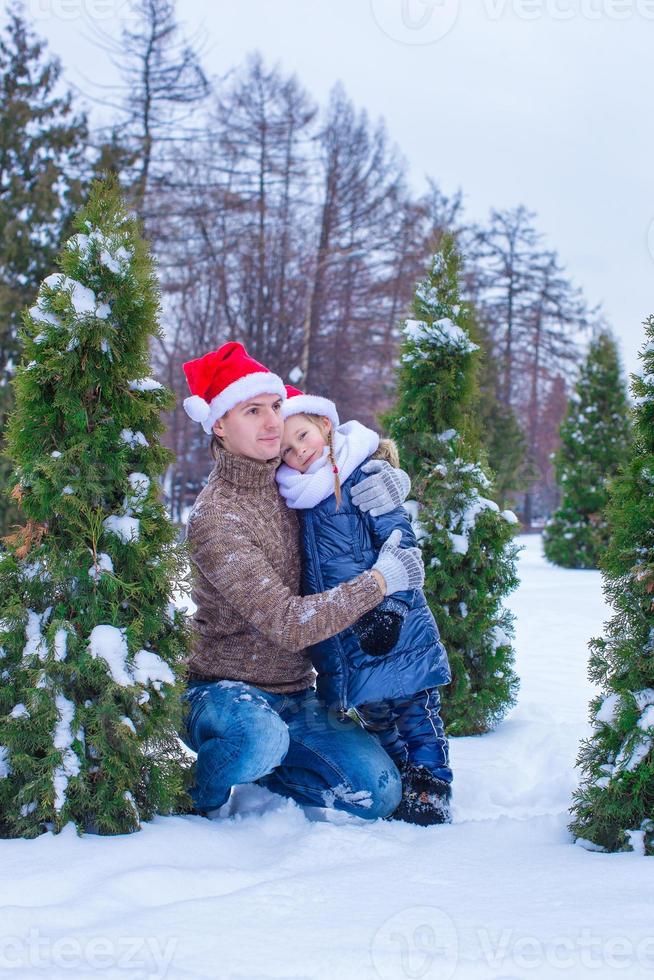 familia feliz en sombreros de santa con árbol de navidad al aire libre foto