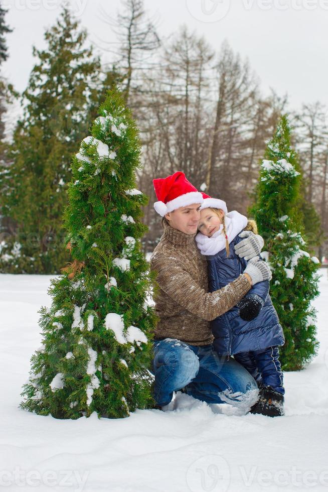 familia feliz en sombreros de santa con árbol de navidad al aire libre foto