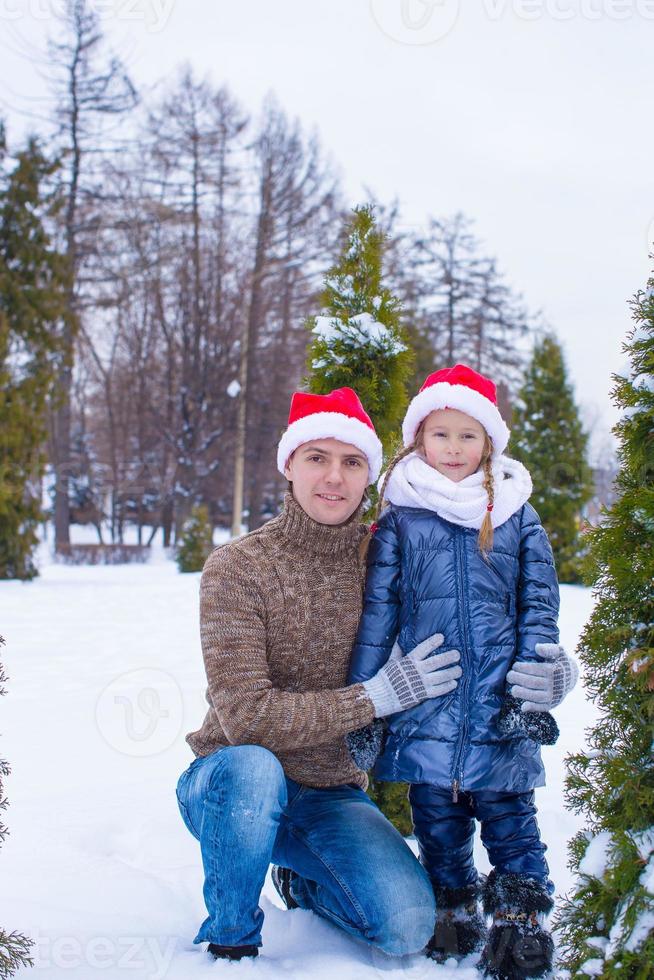 Happy father and kid in Santa hats with christmas tree outdoor photo