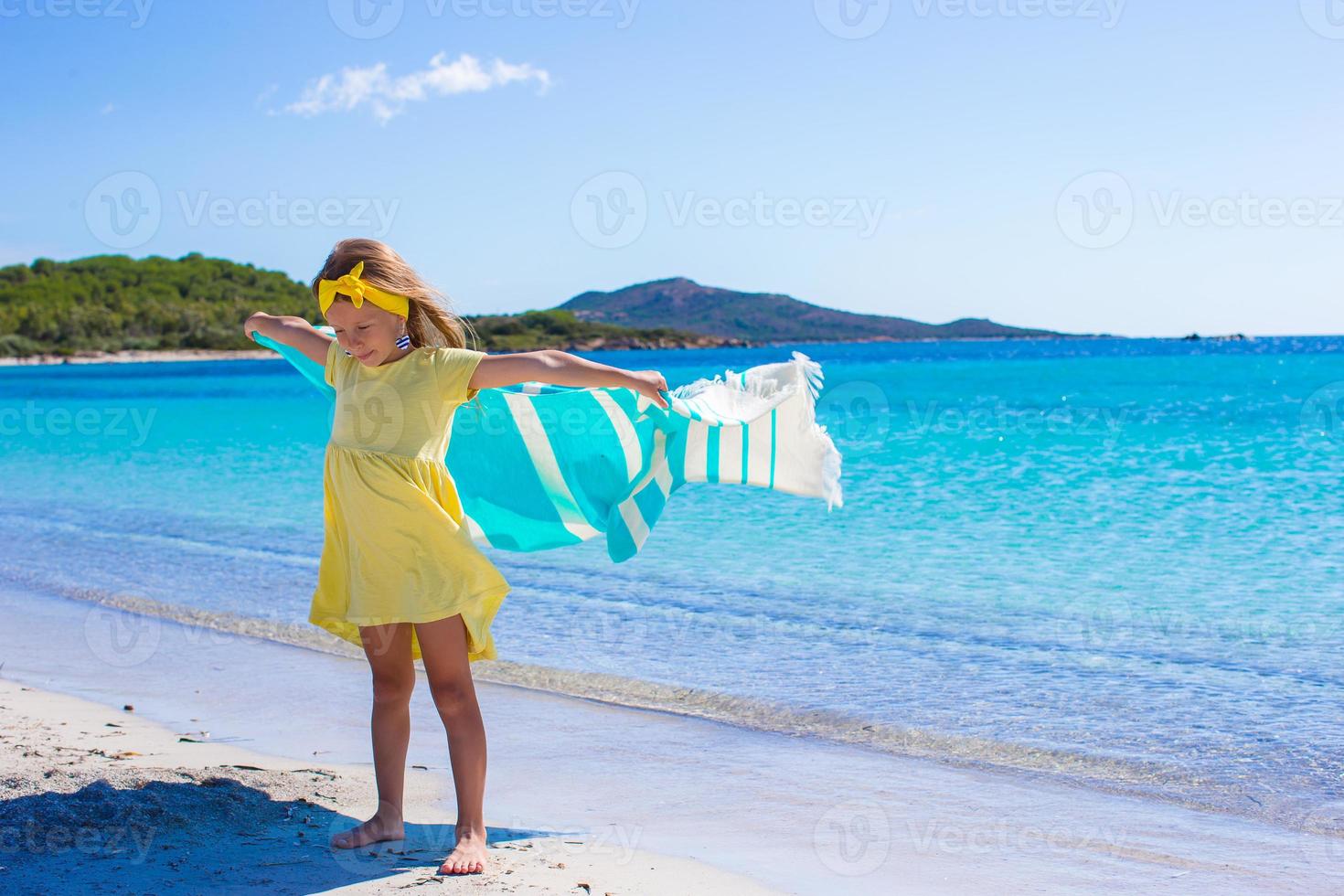 Little adorable girl with beach towel during tropical vacation photo