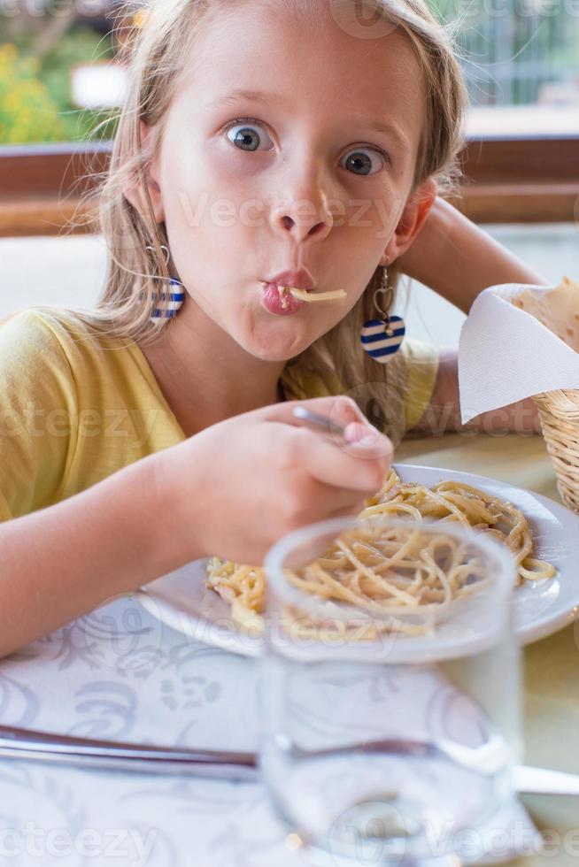 adorable niña comiendo espaguetis en un restaurante al aire libre foto