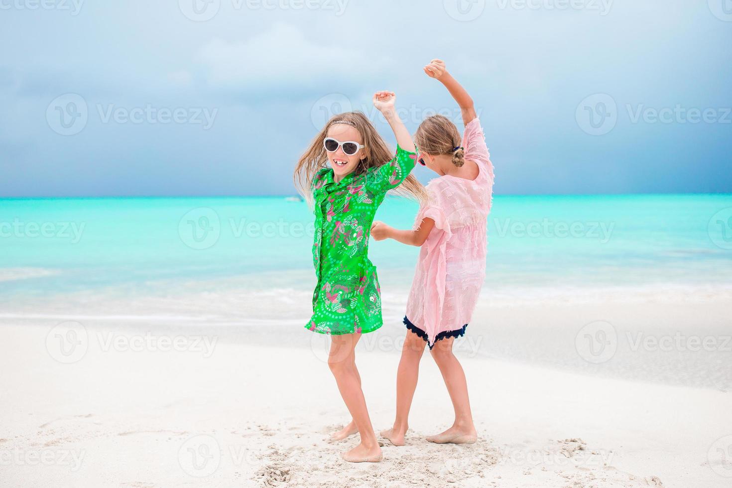 Adorable little girls have a lot of fun on the beach. Two beautiful kids are happpy photo