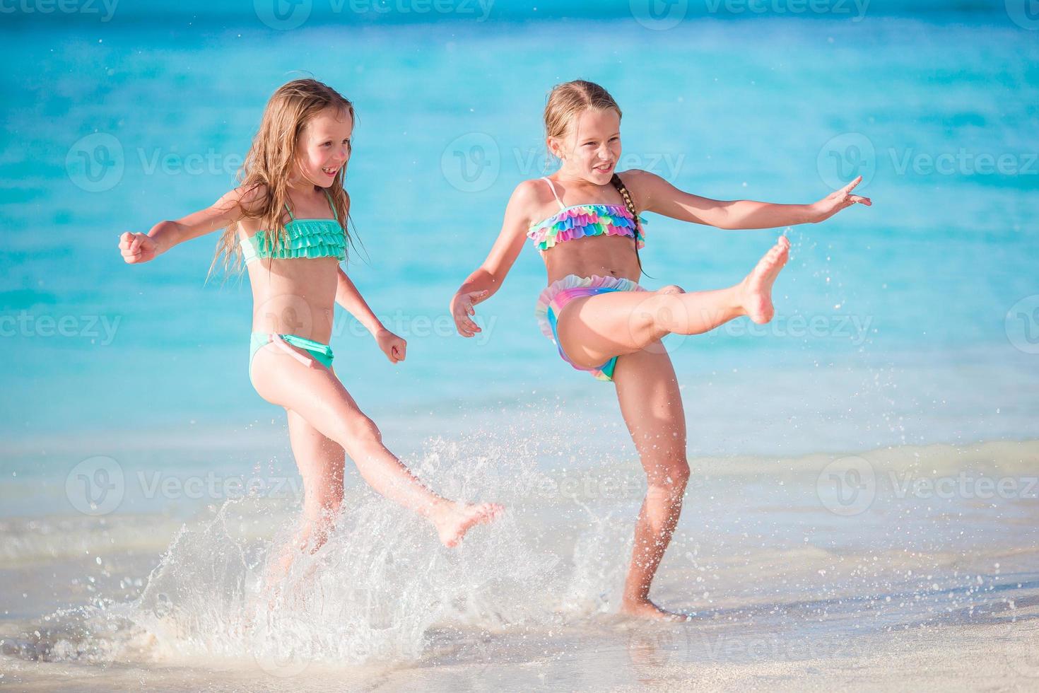 Little happy kids have a lot of fun at tropical beach playing together at shallow water. photo