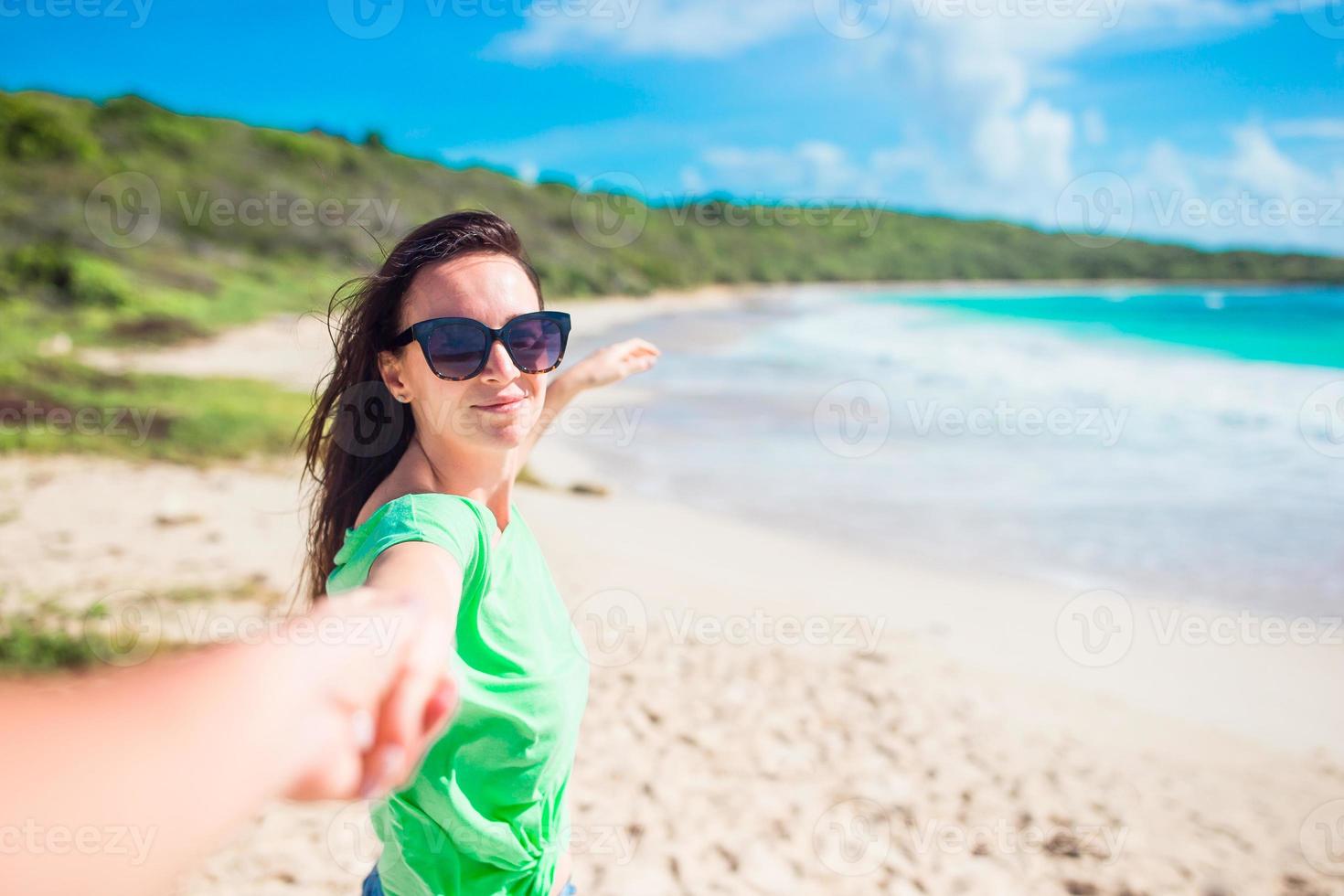 sígueme pov - pareja enamorada divirtiéndose. novio siguiendo a la novia tomados de la mano en la playa salvaje blanca riendo y sonriendo disfrutando de un estilo de vida activo al aire libre foto