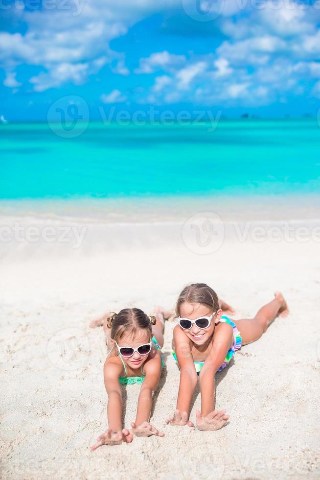 adorables hermanitas en la playa durante las vacaciones de verano tumbadas en arena cálida foto