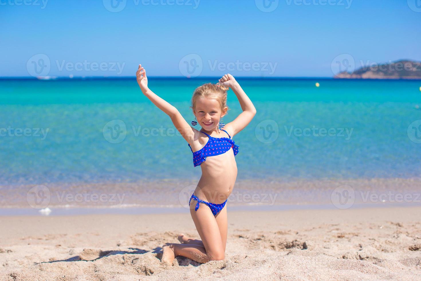 Adorable little girl making wheel on tropical white sandy beach photo